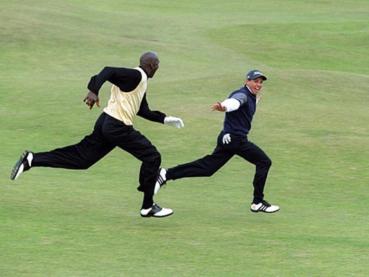 Michael Jordan springer efter en glad golfare som ser ut att försöka likna ett flygplan. De befinner sig på en golfbana.