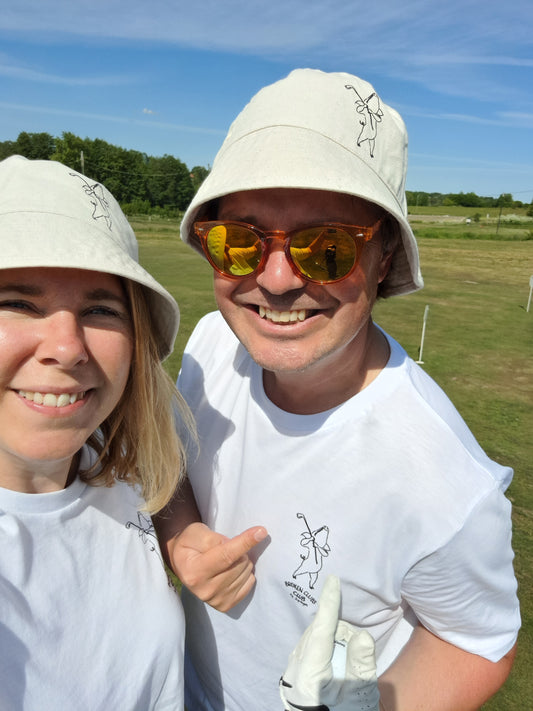 Två personer med golfkläder och bukethat på en golfbana