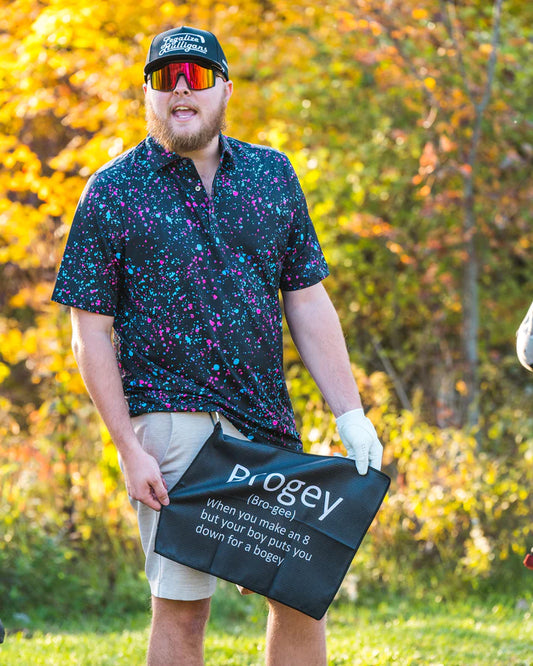 Man i höstlandskap visar upp en golfhandduk som det står Brogey på.