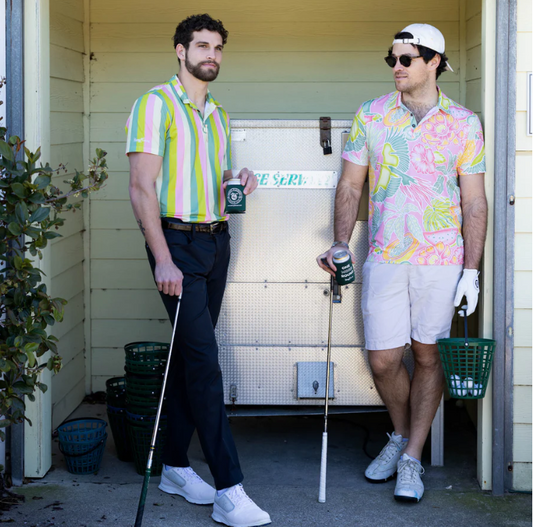 Två golfare med färgglada kläder står vid bollmaskinen vid ranchen, den ena dricker öl och den andra har en hink med golfbollar.