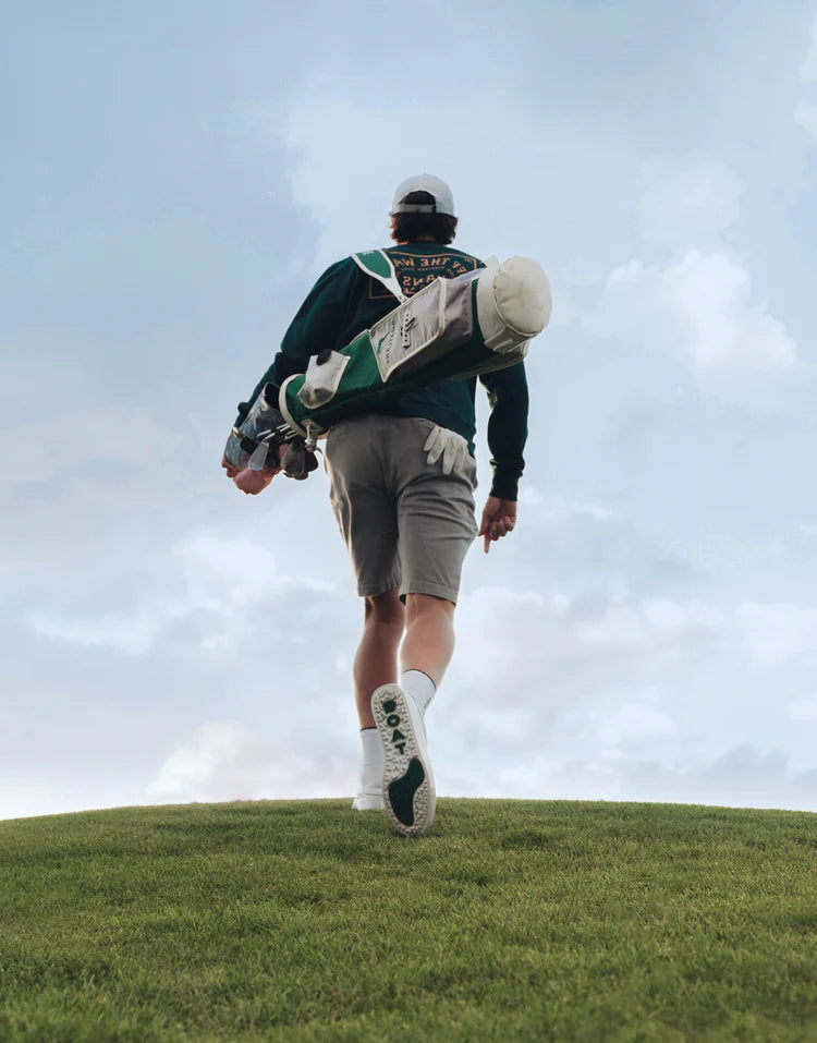 Bild på golfare bakifrån med bag på ryggen och Goatline golfskor.